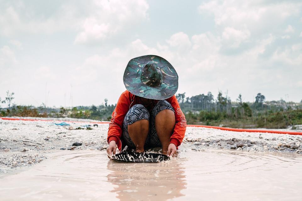 A miner washing gravel in a pan at a mining site